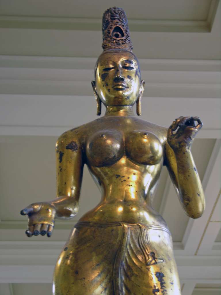 British Museum Top 20 Buddhism 01 Gilded Bronze Tara 1. Standing Tara  Sri Lanka, 8C AD, 143cm high. The statue of Tara, the consort of Avalokiteshvara, is solid cast in one piece of bronze and gilded. The goddess is naked to the waist with a lower garment flowing to her ankles. The marked contrast of the slender waist against heavy breasts and hips is the ideal of feminine beauty. Tara's right hand is shown in the mudra of giving; her left hand is empty but may have held a lotus flower.